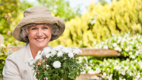 senior woman smiling wearing hat and gardening