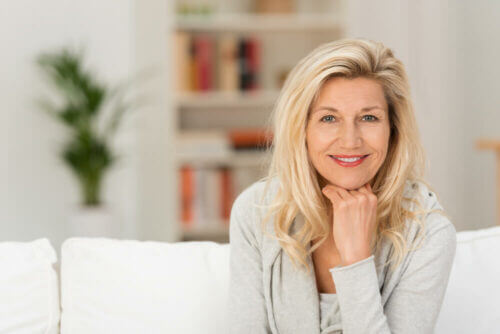 Older woman on couch with blurred background smiling at camera