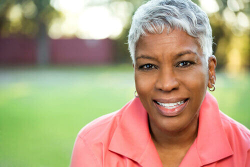 Beautiful senior woman in pink shirt smiling at camera