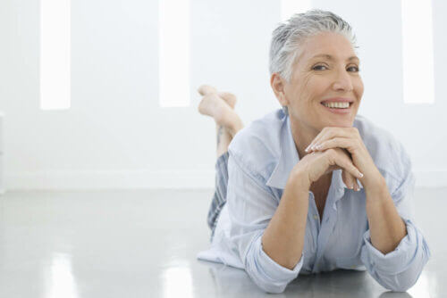 senior woman laying on the floor in a white room