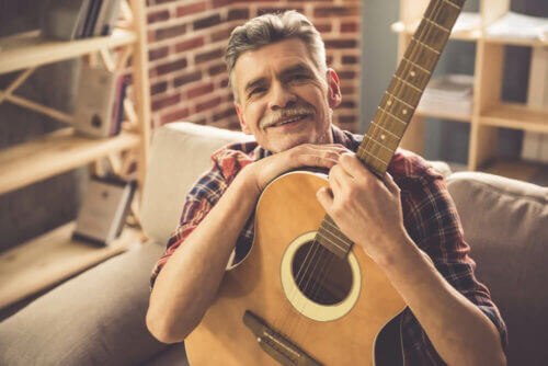 senior man sitting on couch with his guitar